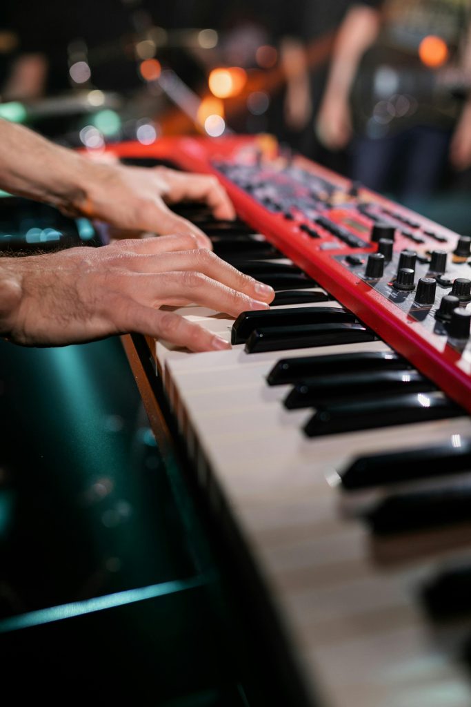 Musician playing a red keyboard live on stage, creating an engaging musical performance.